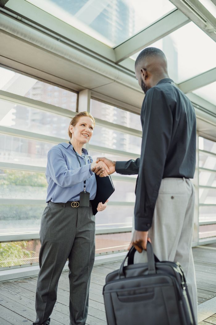 Two business professionals shaking hands in a modern cityscape setting, symbolizing cooperation.
