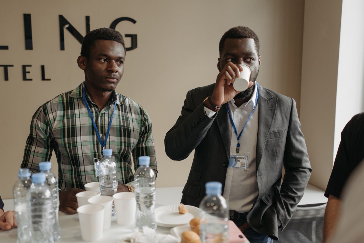 Two businessmen networking at a conference with beverages and name tags.